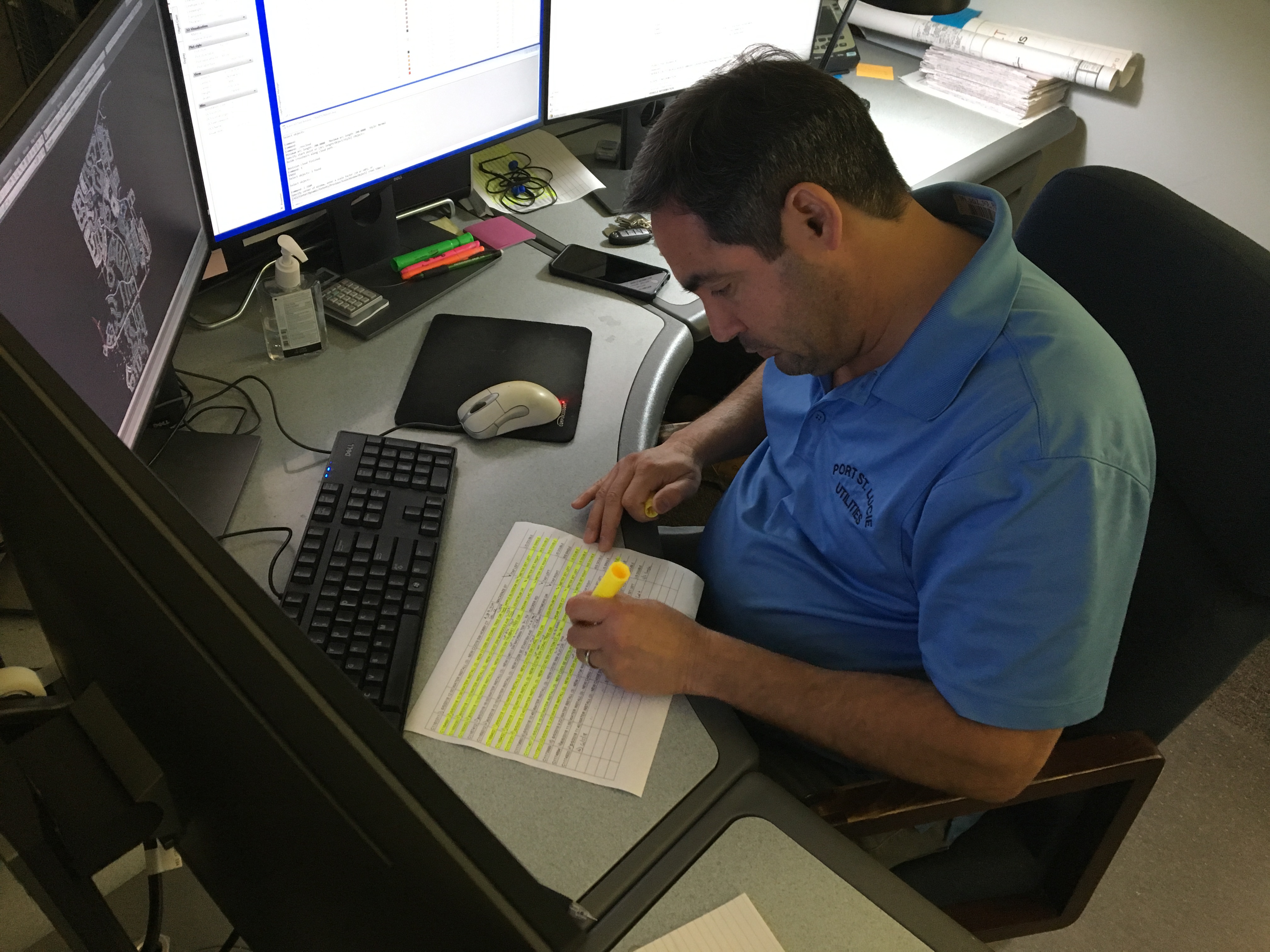 Mapping Technician highlighting spreadsheet at desk